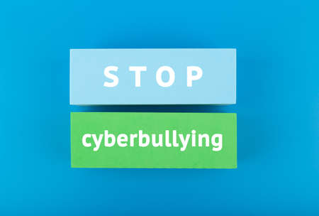 Stop cyberbullying concept. Minimal flat lay with stop cyberbullying inscription on colored rectangles on blue background.の写真素材
