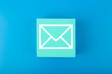 Email marketing, newsletter, promotion information and virtual communication concept. Envelope drawn on toy square against blue background.の写真素材