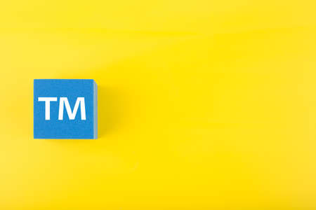 TM trademark sign on blue toy cube on yellow background with copy space. Concept of intellectual property registration and protectionの写真素材