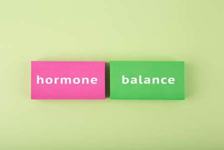 Trendy minimal hormone balance concept in bright green and pink colors. Inscription on multicolored tablets, health care and medical concept.の写真素材