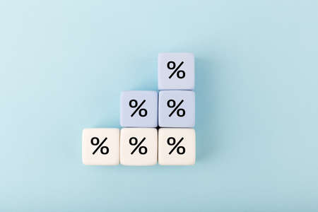Toy blocks as a ladder with percentage sign on bright pastel blue background. Modern concept of inflation, percent, mortgage or interest rate growthの写真素材