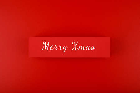 Minimal flat lay Christmas theme. Merry Christmas written on red tabletの写真素材