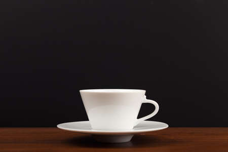 Selective focus, close up of white ceramic coffee or tea cup against dark black background with copy spaceの写真素材