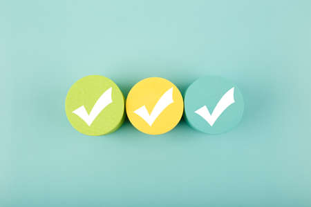 Three white checkmarks on colorful circles against bright aqua blue backgroundの写真素材