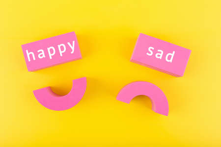 Unhappy and happy smile symbols next to each other on yellow background. Concept of World Smile day, emoji or customer satisfaction evaluationの写真素材