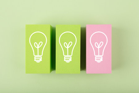 Creativity and fresh idea concept. Light bulbs on green and pink toy blocks against bright pastel green backgroundの写真素材