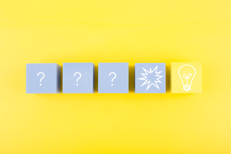 Creativity, brainstorming and fresh ideas concept. Light bulb and question signs drawn on toy cubes...