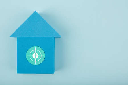 Mortgage, loan or saving money for home and investing in real estate trendy concept. Blue toy house with white target in the middle against bright blue background with copy spaceの写真素材