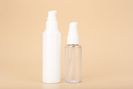 Concept of skin care and beauty products for daily skin care. Transparent bottle with liquid face gel or foam and skin cream or lotion against bright beige background with copy spaceの写真素材