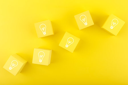 Creativity, brainstorming and fresh ideas concept. Light bulbs drawn on toy cubesの写真素材