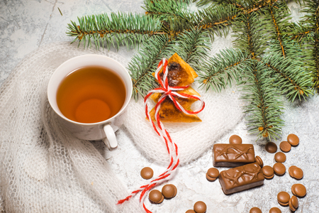 A cup of tea with chocolate , a branch of a spruce tree on a textured backgroundの写真素材