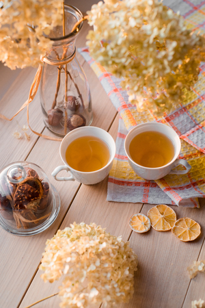 Autumn composition. Two mugs of hot tea on a linen yellow napkin. Dried hydrangea, lemon, chestnut, cinnamon.の写真素材
