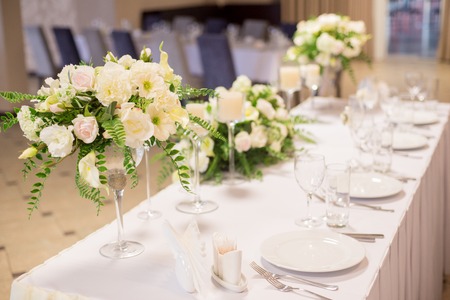 Wedding decor in the interior. White flowers on the table. Serving the table with glasses.の写真素材