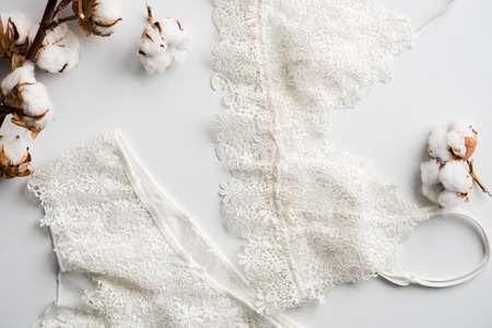 Set of lingerie, beige with black white ribbons. On white background on white background decorated with cotton flowersの写真素材