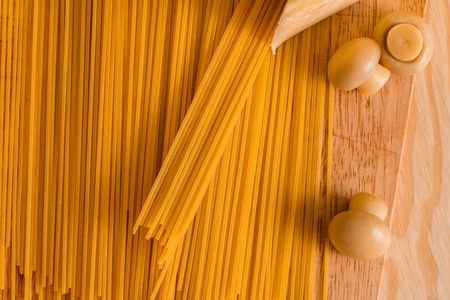 Preparation of spaghetti with cheese mushrooms. Eggs and sour cream sauce, champignons on a cutting board on a wooden texture background. Copy place for inscriptionの写真素材