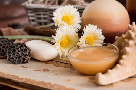 Spa accessories with soap, bowl with dried chamomile flowers, A piece of white soap, liquid brown soap, seashell shell, aromatherapy candles, dried lotus flower seeds. On a wooden vintage backgroundの写真素材