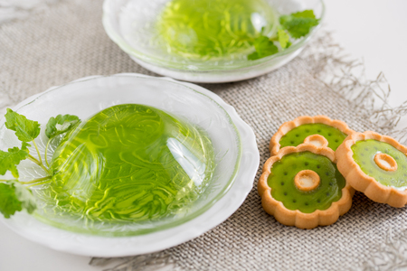 Green jelly with mint leaves in glass on wooden background. Juice with ice in gelatin. on a linen napkin on a white background.の写真素材