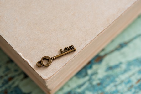 Closed book, the key symbol of Valentine's Day. Vintage old heart. On a textured blue green background with cracked colors of crockelerの写真素材