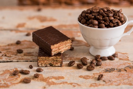 Cup of coffee with grains scattered on a wooden background. chocolate waffle, sweet dessertの写真素材