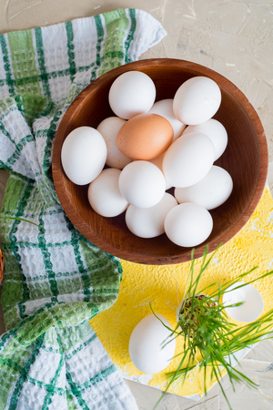 Easter grass growing in egg shell, shallow focus Yellow background, white eggs in a basket on a wooden background, Green checkered towel napkinの写真素材