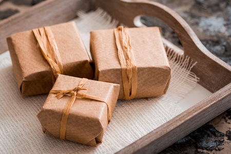 Three gift boxes in a kraft wrapper on a gray concrete background on wooden table.の写真素材