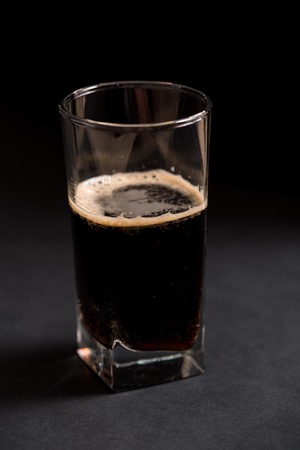 Glass of dark beer over a dark textured wooden backgroundの写真素材