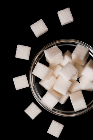 Pieces of sugar refined sugar on a black background, scattered chaoticallyの写真素材
