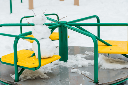 chubby snowman and de focused background, Spring snow and puddles. on the children's carouselの写真素材