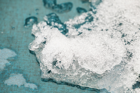melting snow on a wooden blue background, icicles and ice as a background. Outgoing winter, spring weatherの写真素材