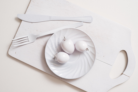 White fork knife plate on an old wooden plank tray. Art idea white tomatoes, all in one colorの写真素材