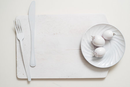 White fork knife plate on an old wooden plank tray. Art idea white tomatoes, all in one color