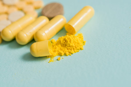 yellow pills on a blue background Open capsule, powdered medicine. copy space