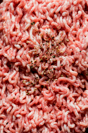 minced pork, Minced meat texture close up - top view minced meat raw fresh macro. Close-up with pepper, salt spices. cooking cutlets.の写真素材