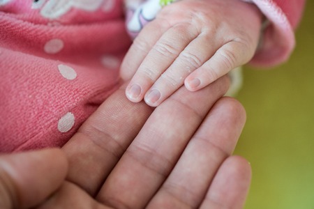 Newborn baby, closeup of fingers of fingers on hand of mother offering him love and securityの写真素材