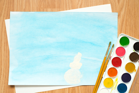 children's drawing with colored pencils and watercolors. winter tree in the snow, a snowman on a blue backgroundの写真素材