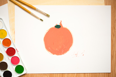 children's drawing with colored pencils and watercolors. red apple, orange orange on a white sheet of colored paperの写真素材