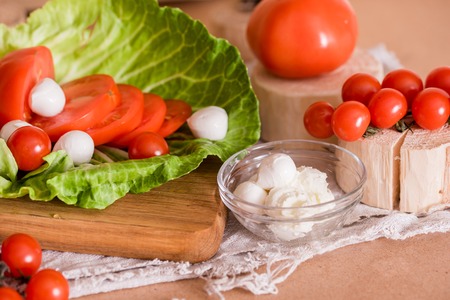 cherry tomatoes, green cabbage, white feta cheese, cooking, salad on a wooden table and cutting boardの写真素材