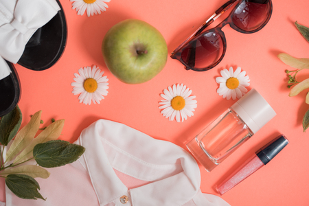 Flat Lay Shot Of Female Holiday Clothing And Accessories on a pink background. Camomile flowers and appleの写真素材