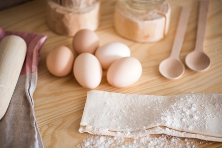 Preparation of the dough. Ingredients for the dough - Eggs and flour with a rolling pin. On wooden backgroundの写真素材