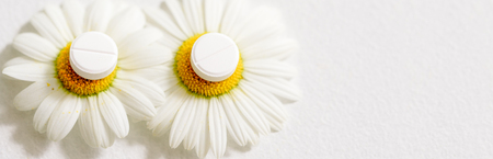 Banner chamomile flowers, homeopathic medicine. white tablets on yellow pollenの写真素材