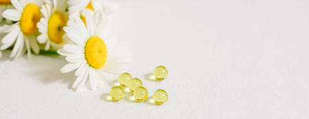 Banner chamomile flowers, homeopathic medicine. white tablets on yellow pollenの写真素材