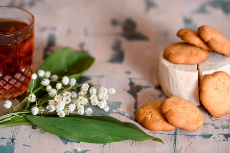 a Cup of tea, nuts, bouquet of lilacs on a wooden table.の写真素材