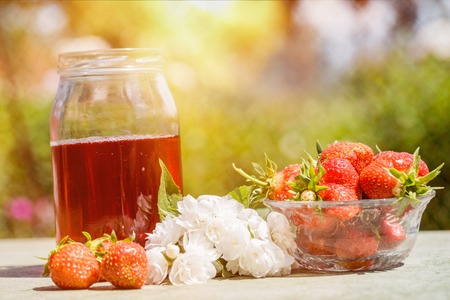 Strawberry lemonade, cocktail with ice and mint in glasses and jug with green background outdoors, copy space. Refreshing summer berry drink. Sparkling drink in glasses.の写真素材