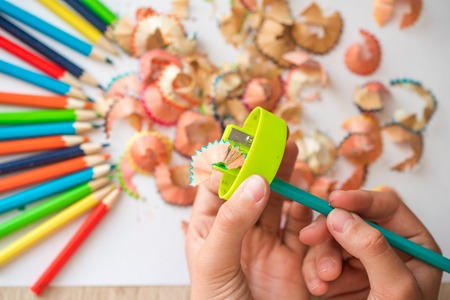 Sharpened color pencil and pencil shavings. Hands of a child on a white background.の写真素材