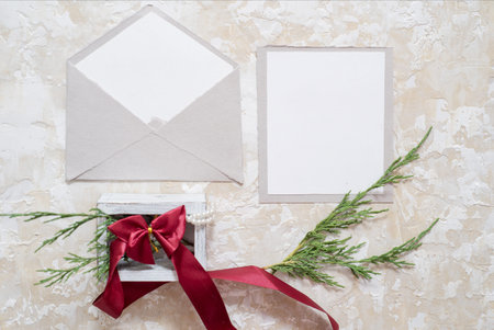 Top view of envelope and blank greeting card with rose flowers on white wooden background