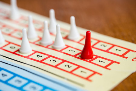 the board game with color pawns, The red chip is in the lead, white competitors