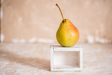 Autumn pear in a white old wooden small box. Life style. Yellow autumn leaves on a concrete light background. Selective focus, space for text.の写真素材
