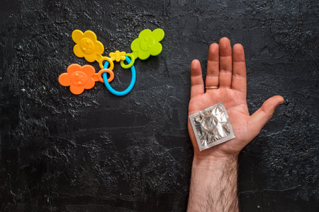Male hand opens a condom, next rattle.
