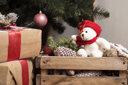 Bear wearing Santa hat with Christmas gift boxes on a white carpet at night.の写真素材
