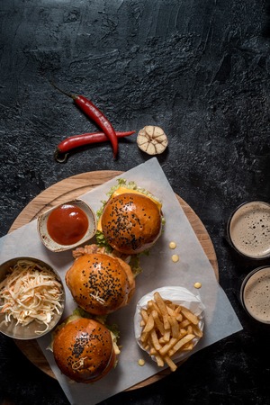 Set three burger, french fries, ketchup sauce, salad and two glasses of dark beer.の写真素材
